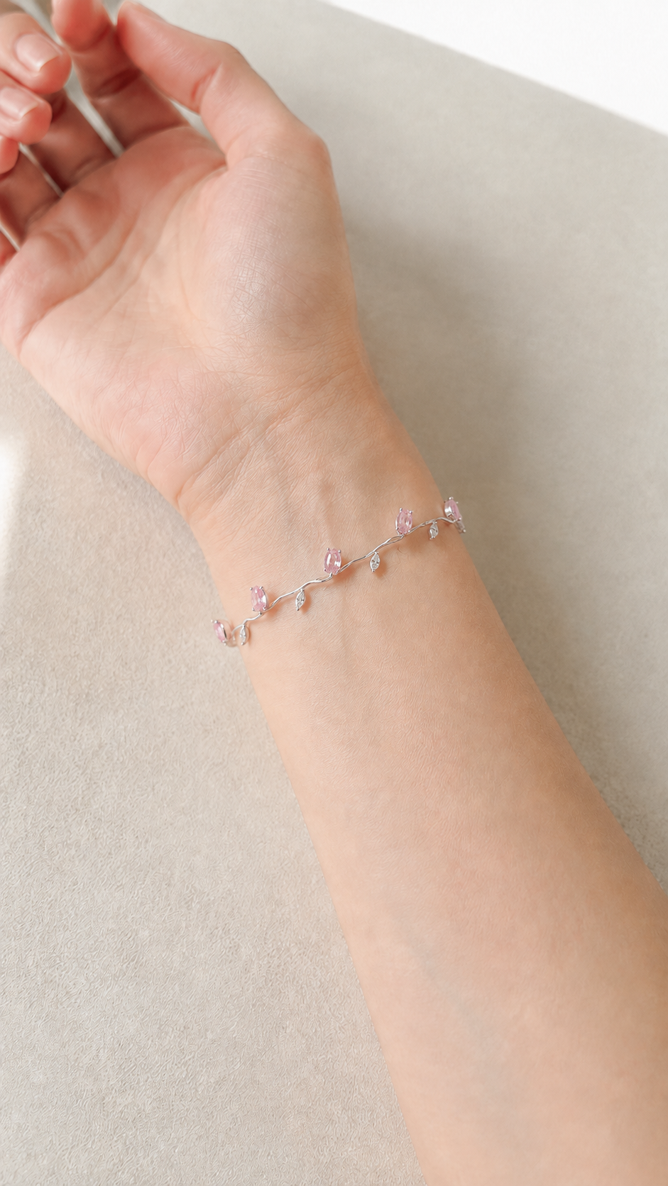 Tulip bracelet design preview in pink, worn on a wrist: closed oval tulip buds on a slender wavy silver-tone vine with fine leaves